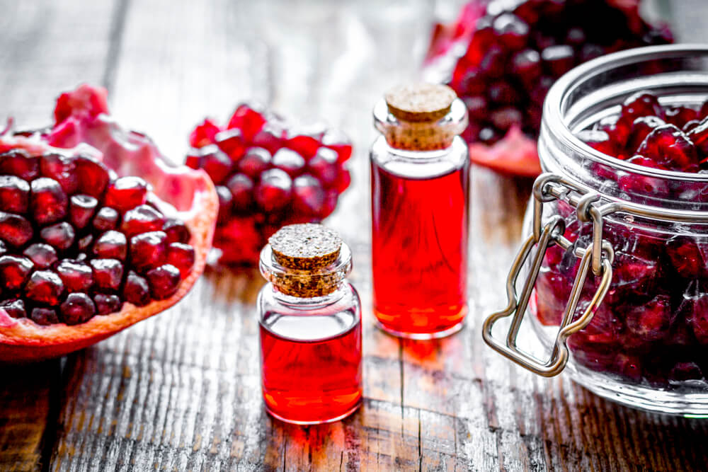 Sliced,Pomegranate,And,Extract,In,Glass,On,Wooden,Background